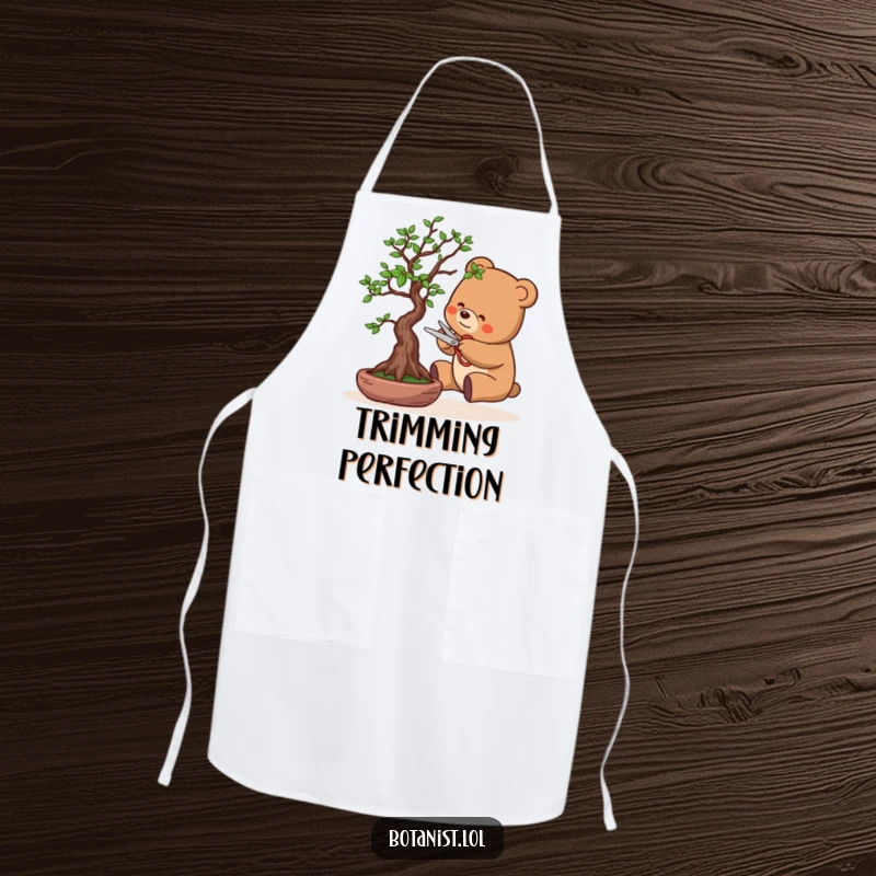 Funny apron with a bear character carefully pruning a bonsai tree using tiny scissors, adding a humorous touch to kitchen wear.