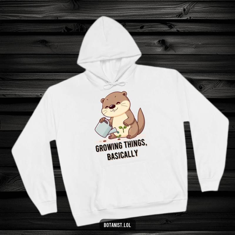 Funny hoodie showcasing a cute otter carefully watering a tiny seedling with a watering can, a heartwarming and humorous scene.