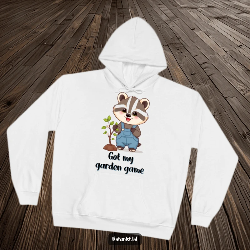 Funny hoodie showcasing a cheerful badger wearing overalls, pruning a small tree, a heartwarming and humorous scene of dedication.