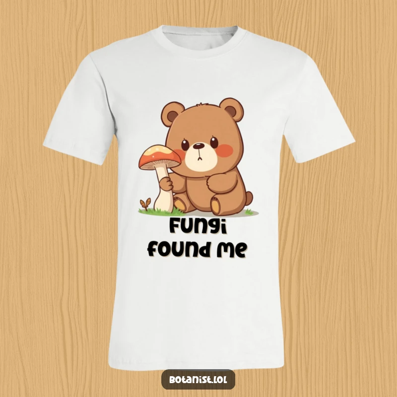 Funny t-shirt graphic of a surprised bear, eyes wide with curiosity, examining a comically giant mushroom in the woods.